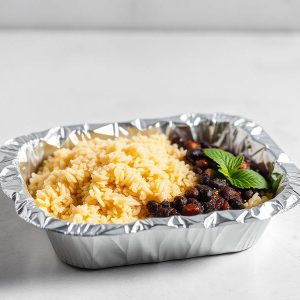 Foil takeout tray with yellow rice and black beans, garnished with a mint leaf.