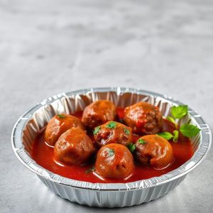 Meatballs in tomato sauce served in a disposable aluminum tray, garnished with parsley.