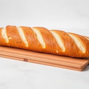 Golden-brown baguette with diagonal slashes resting on a wooden cutting board