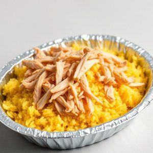 Foil takeout container filled with saffron-yellow rice topped with shredded chicken pieces in the center.